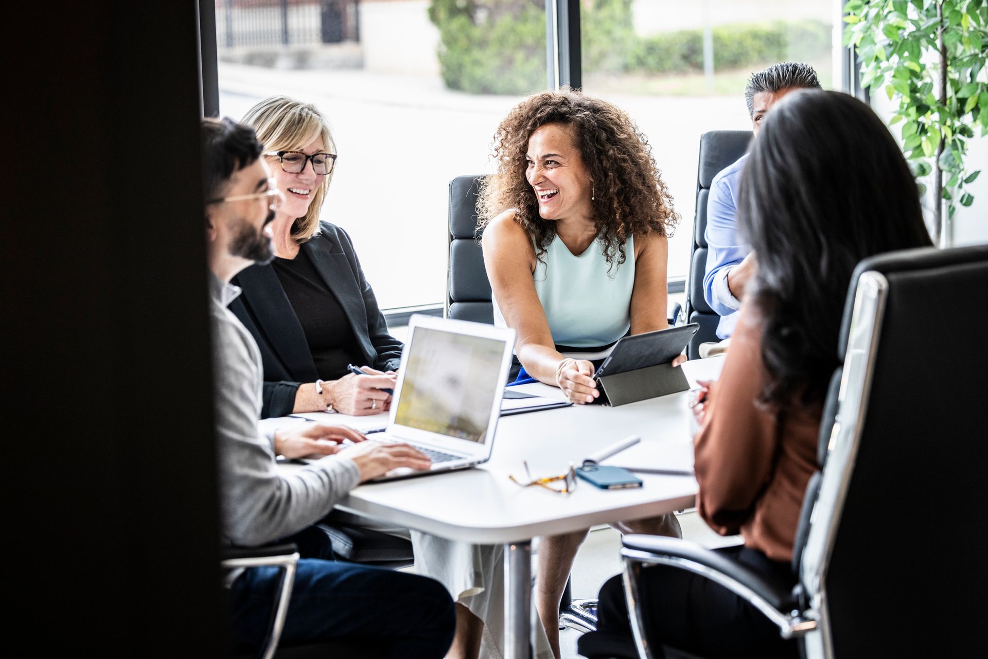 Un gruppo di persone è seduto attorno a un tavolo con i propri computer portatili.