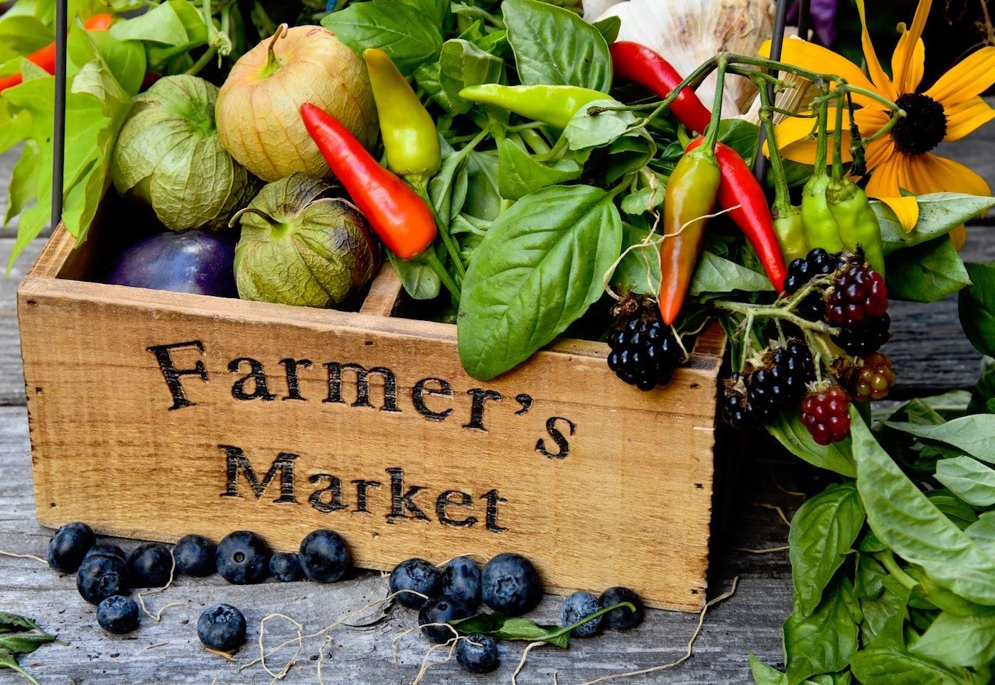 A wooden box filled with fruits and vegetables is labeled farmer 's market