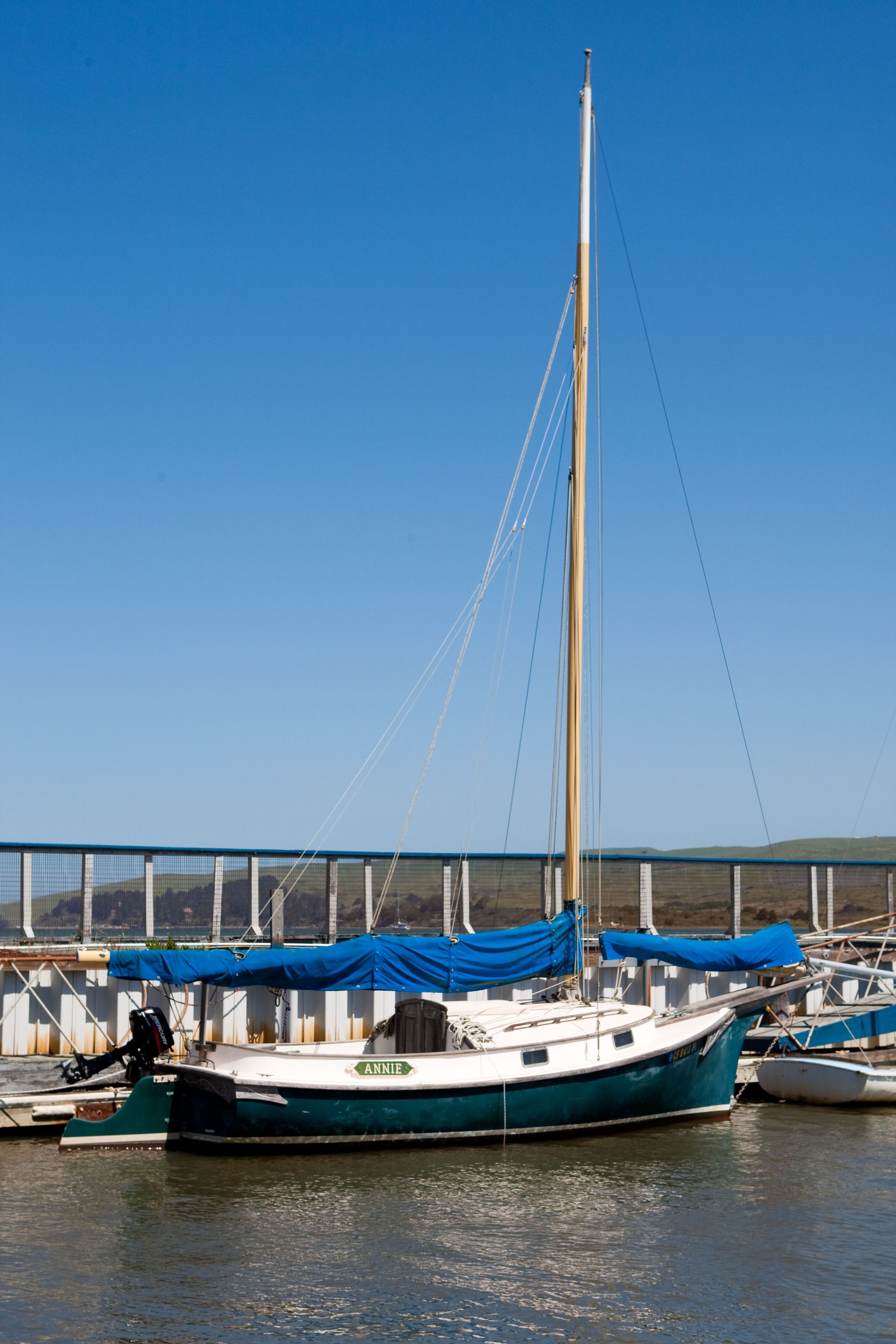 A sailboat with a blue sail is docked in the water