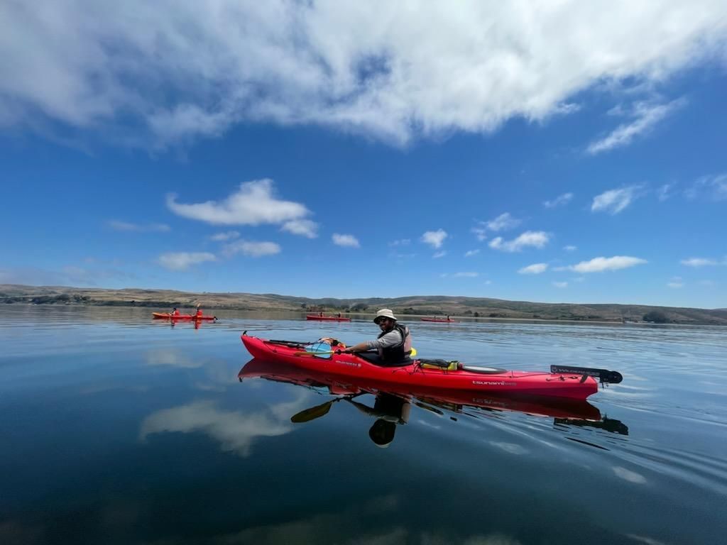 A person is riding a red kayak on a lake.