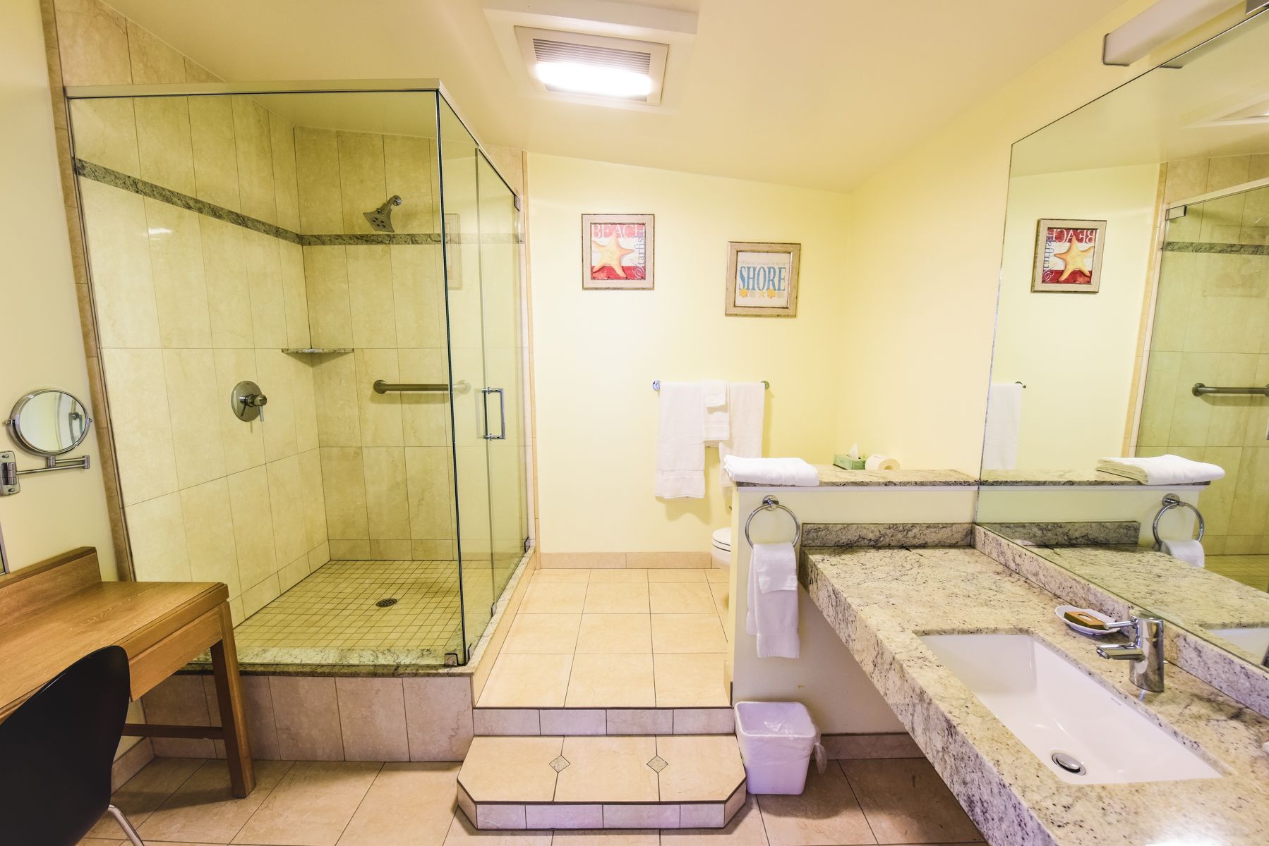 A bathroom with a sink , mirror and walk in shower.