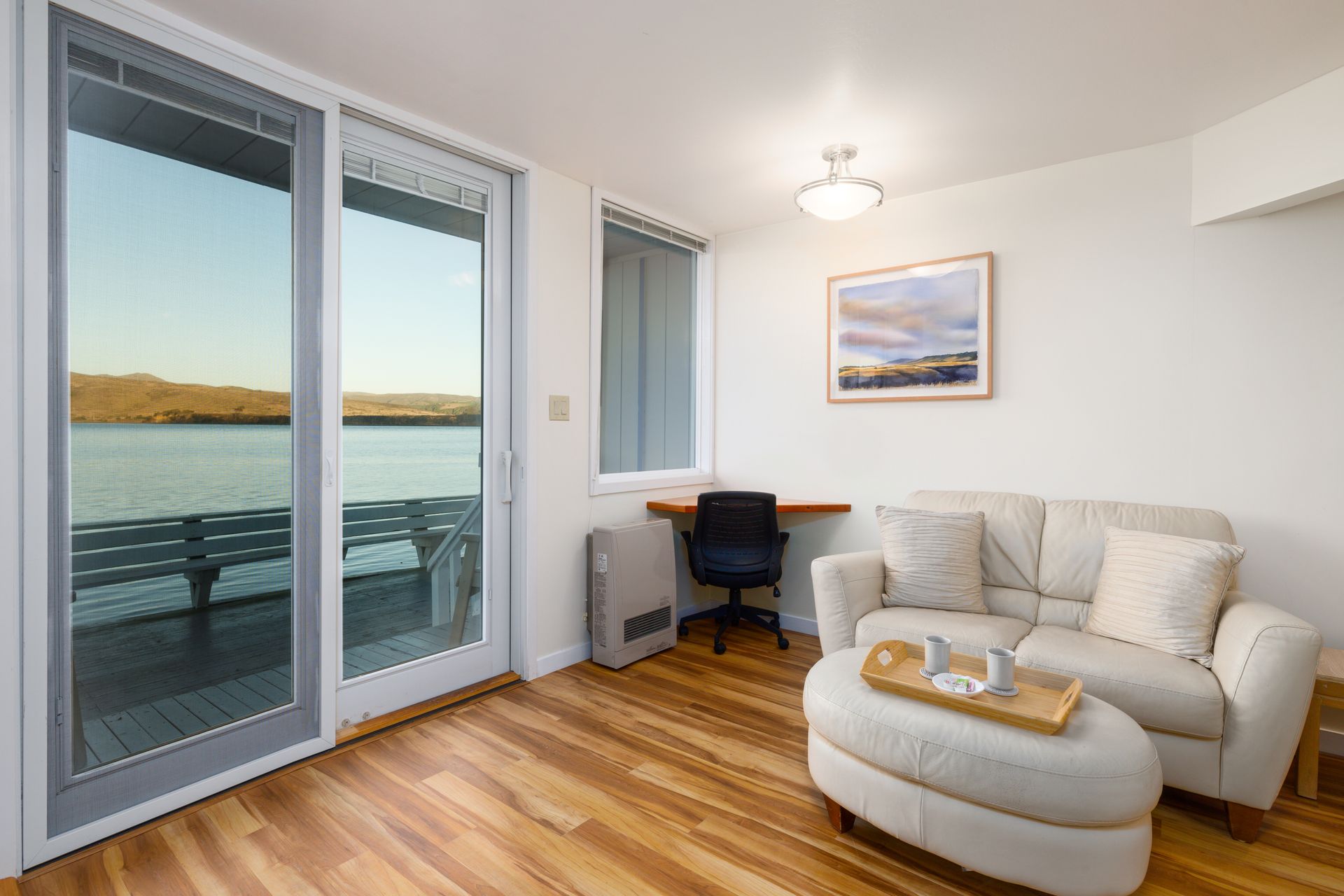 A living room with a couch , chair and ottoman with a view of the water.