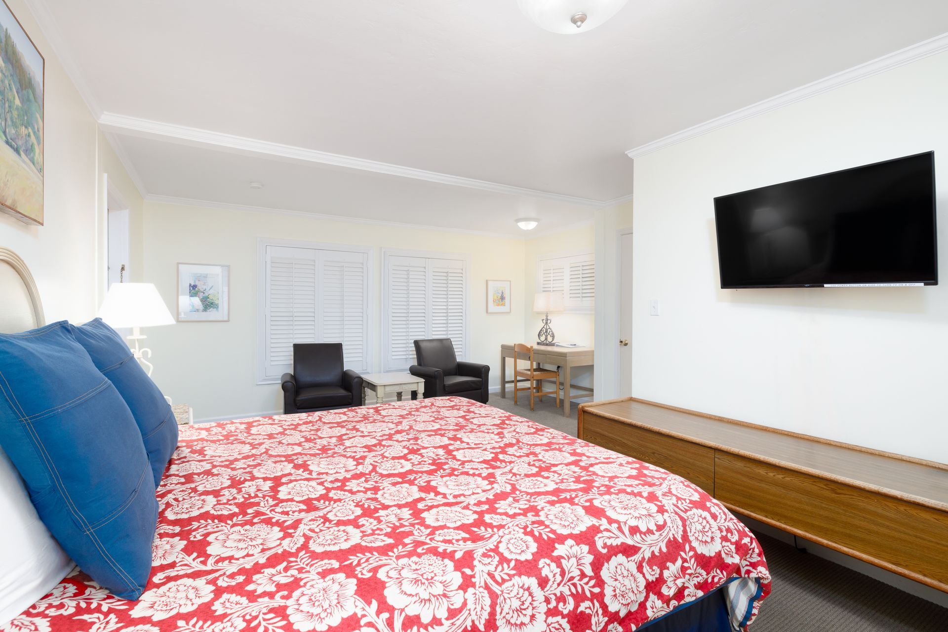 A hotel room with a king size bed and a flat screen tv on the wall.