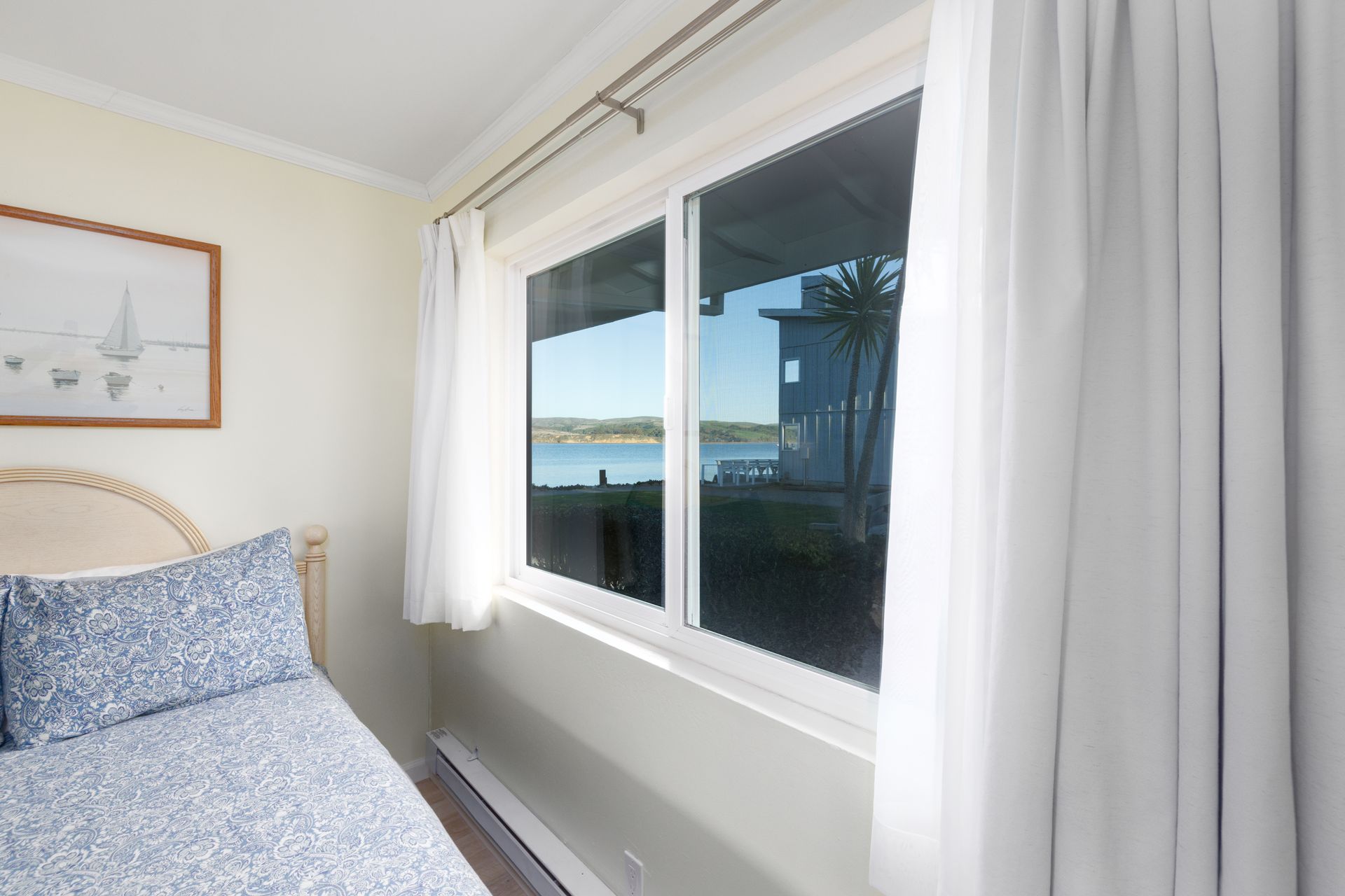 A bedroom with a bed and a window with a view of the ocean.