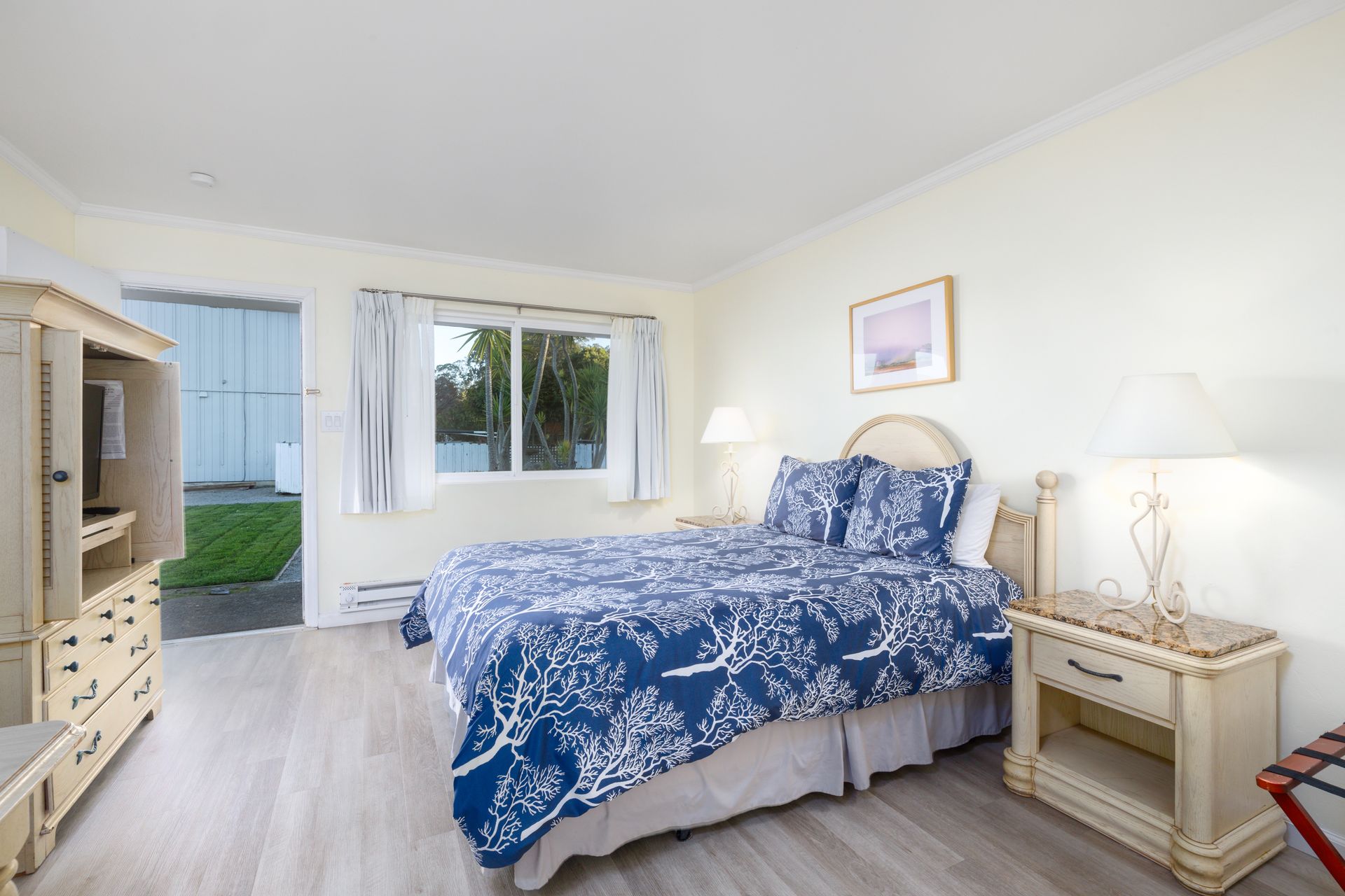 A bedroom with a king size bed , nightstand , dresser and television.