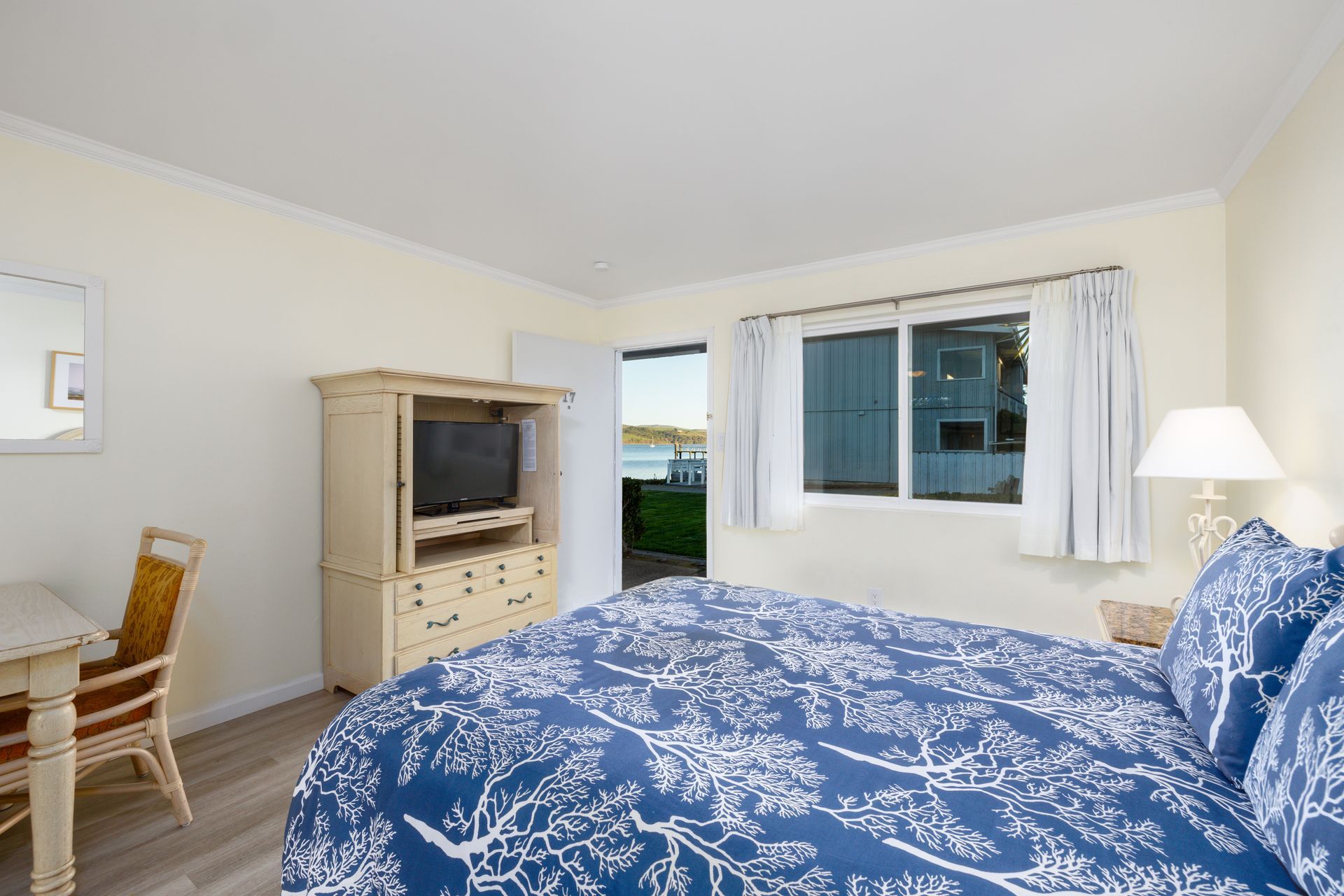 A hotel room with a king size bed , television , desk and chair.