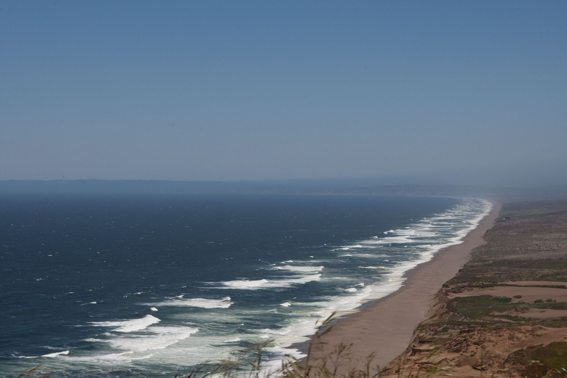 An aerial view of a beach with waves crashing on the shore