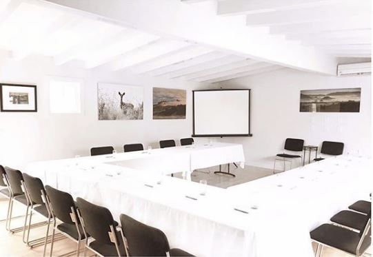 A conference room with tables and chairs and a projector screen