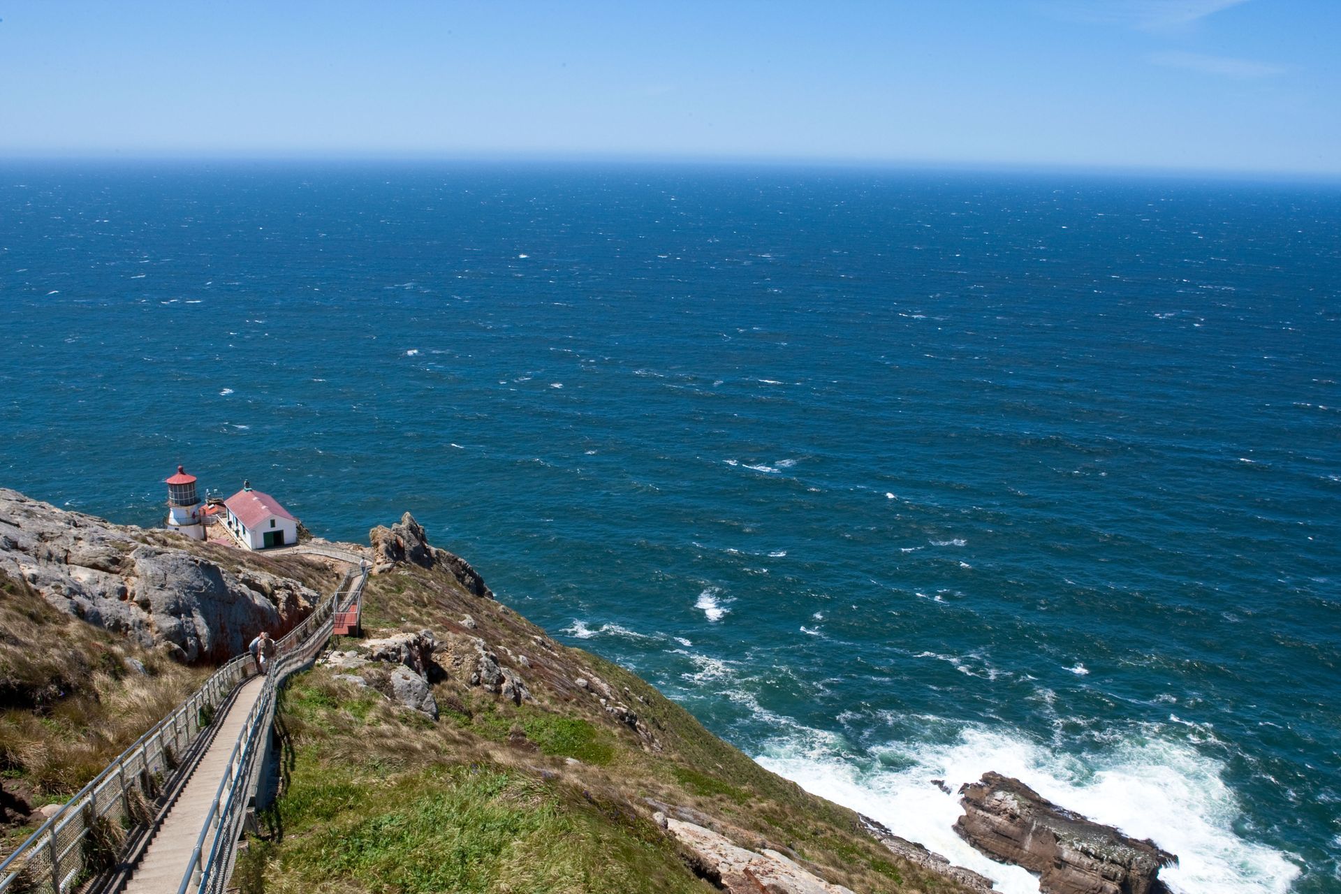 There is a lighthouse on the cliff overlooking the ocean.