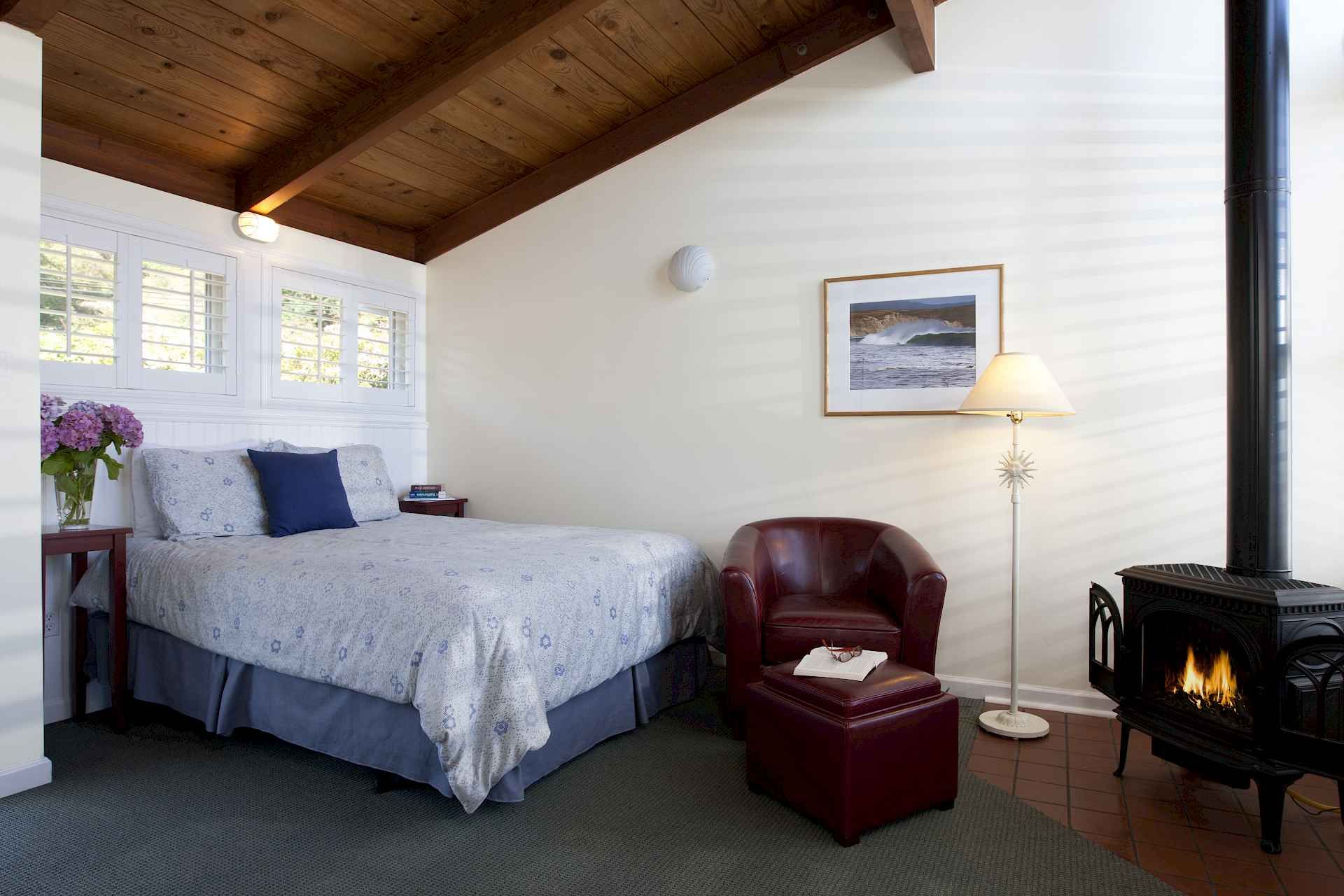 A bedroom with a bed a chair and a fireplace