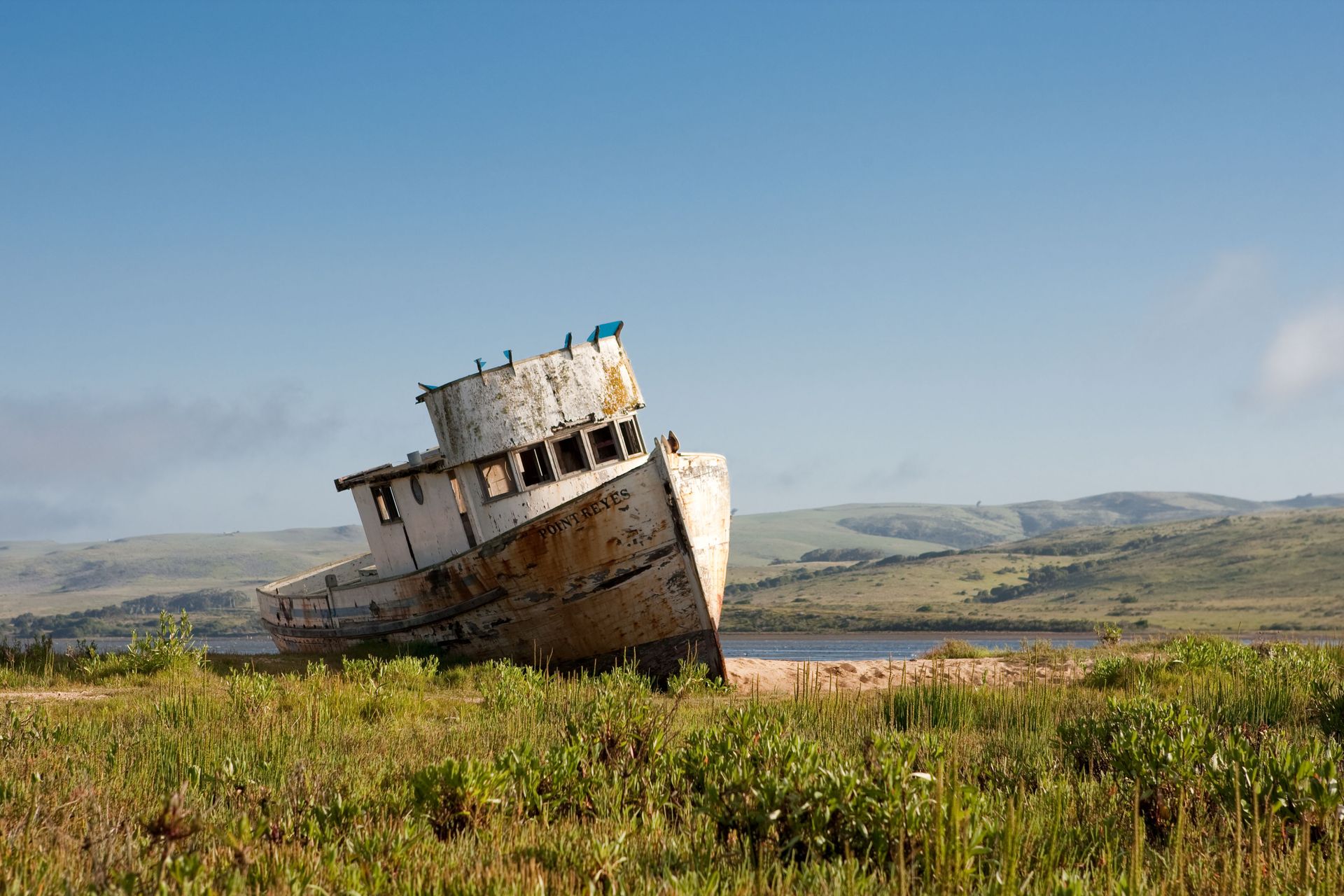 An old boat is sitting in the middle of a grassy field.
