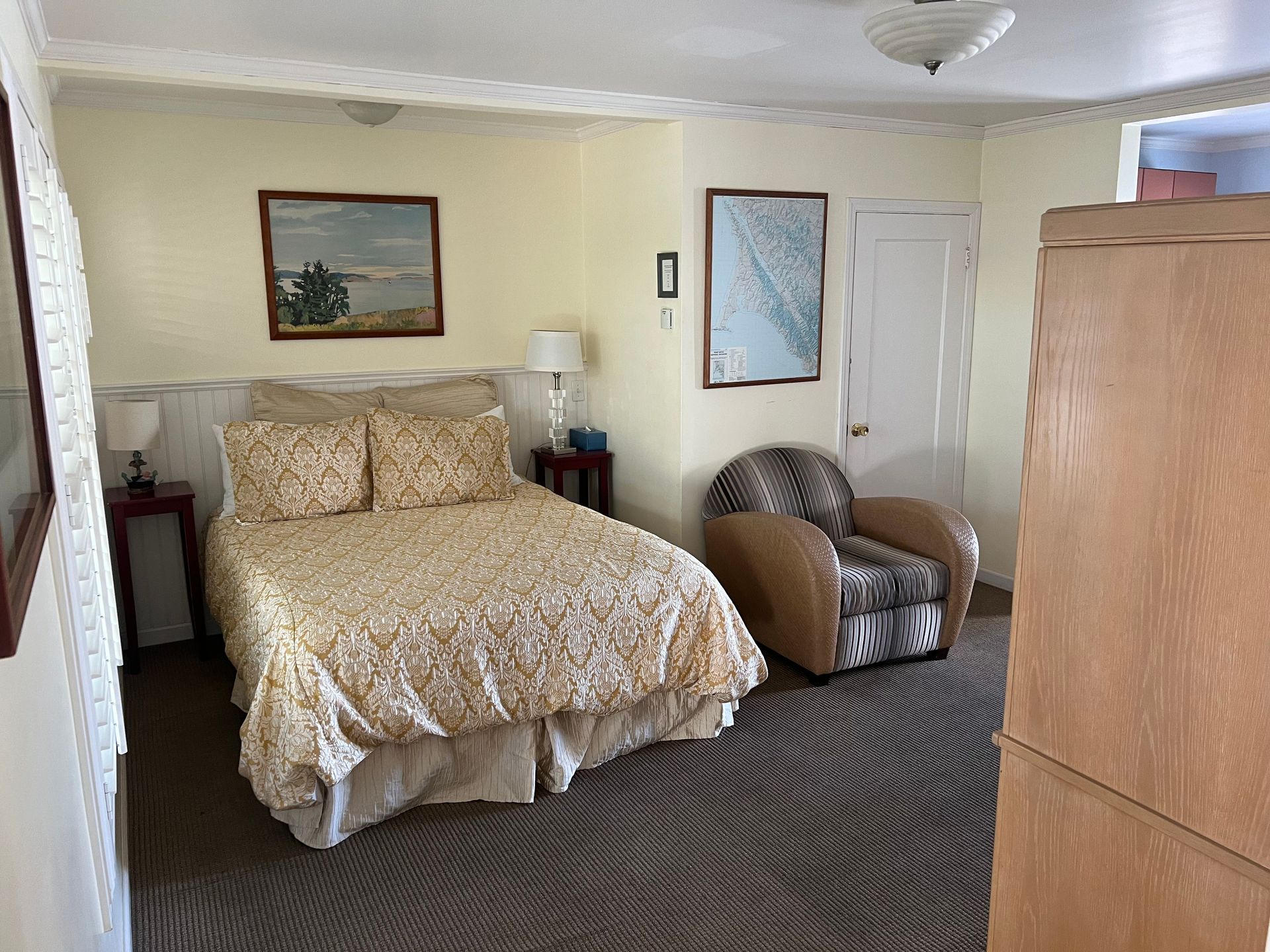 A bedroom with a bed , chair and dresser.