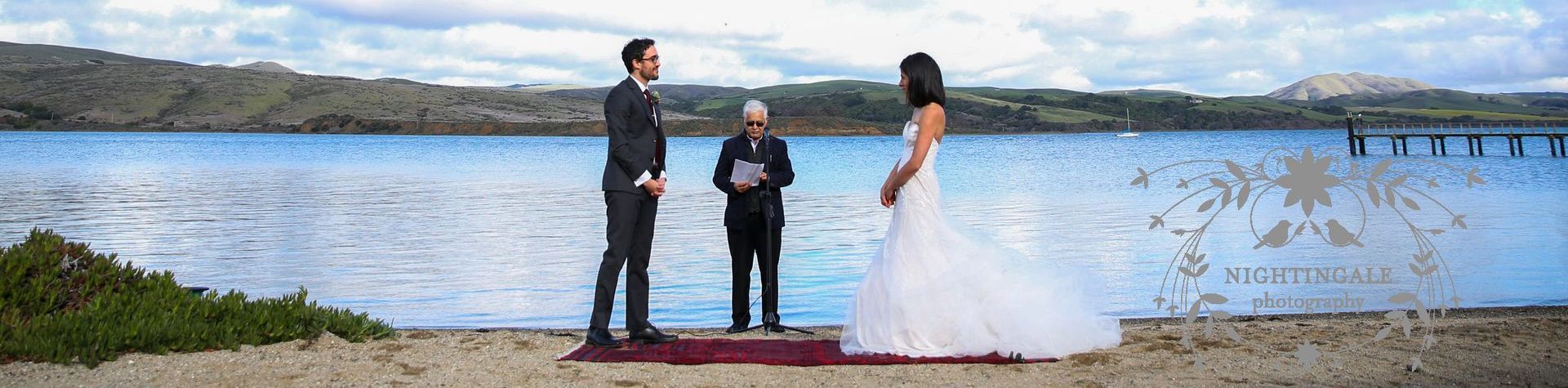 A bride and groom are getting married in front of a lake.