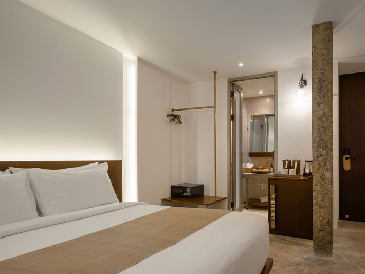 Modern bedroom with a large bed, warm lighting, and a small desk by a glass partition