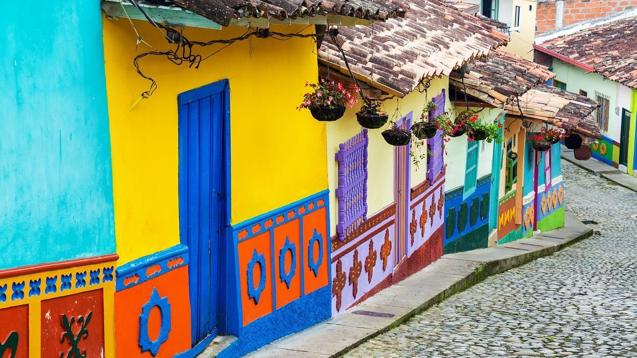 Colorful houses line a cobblestone street. The houses have bright blue, yellow, and purple paint.
