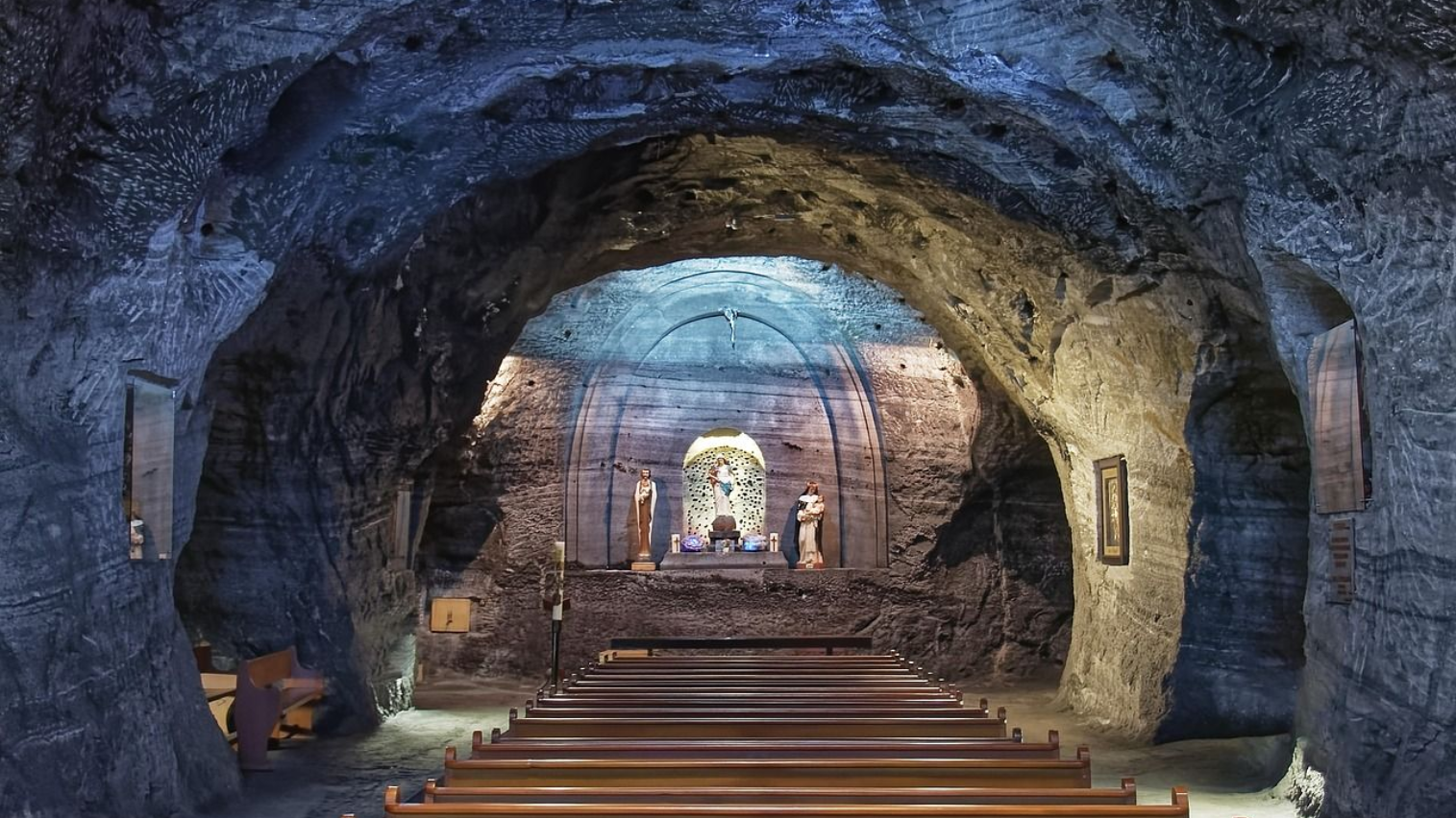 Church in a salt mine, carved from rock salt, with pews and altar. Blue and gold lighting.