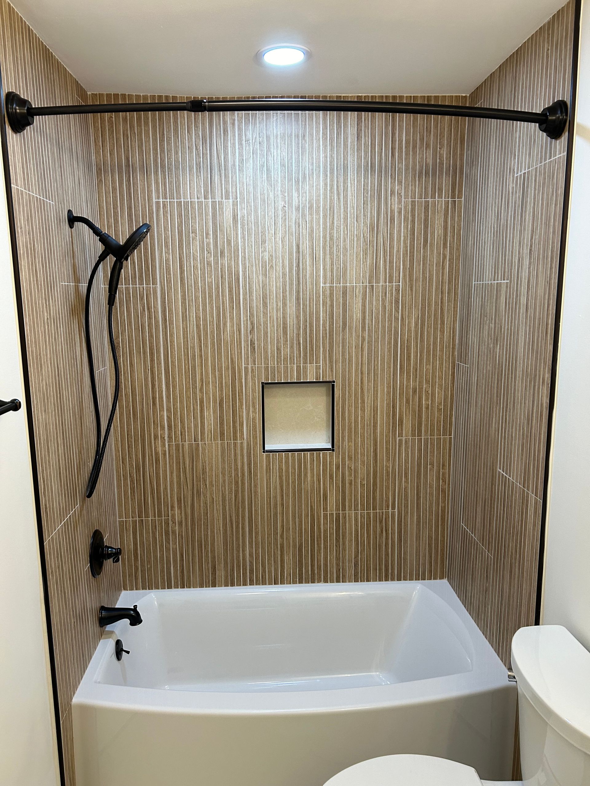 Modern white bathroom with a freestanding tub facing large windows and a calm ocean view