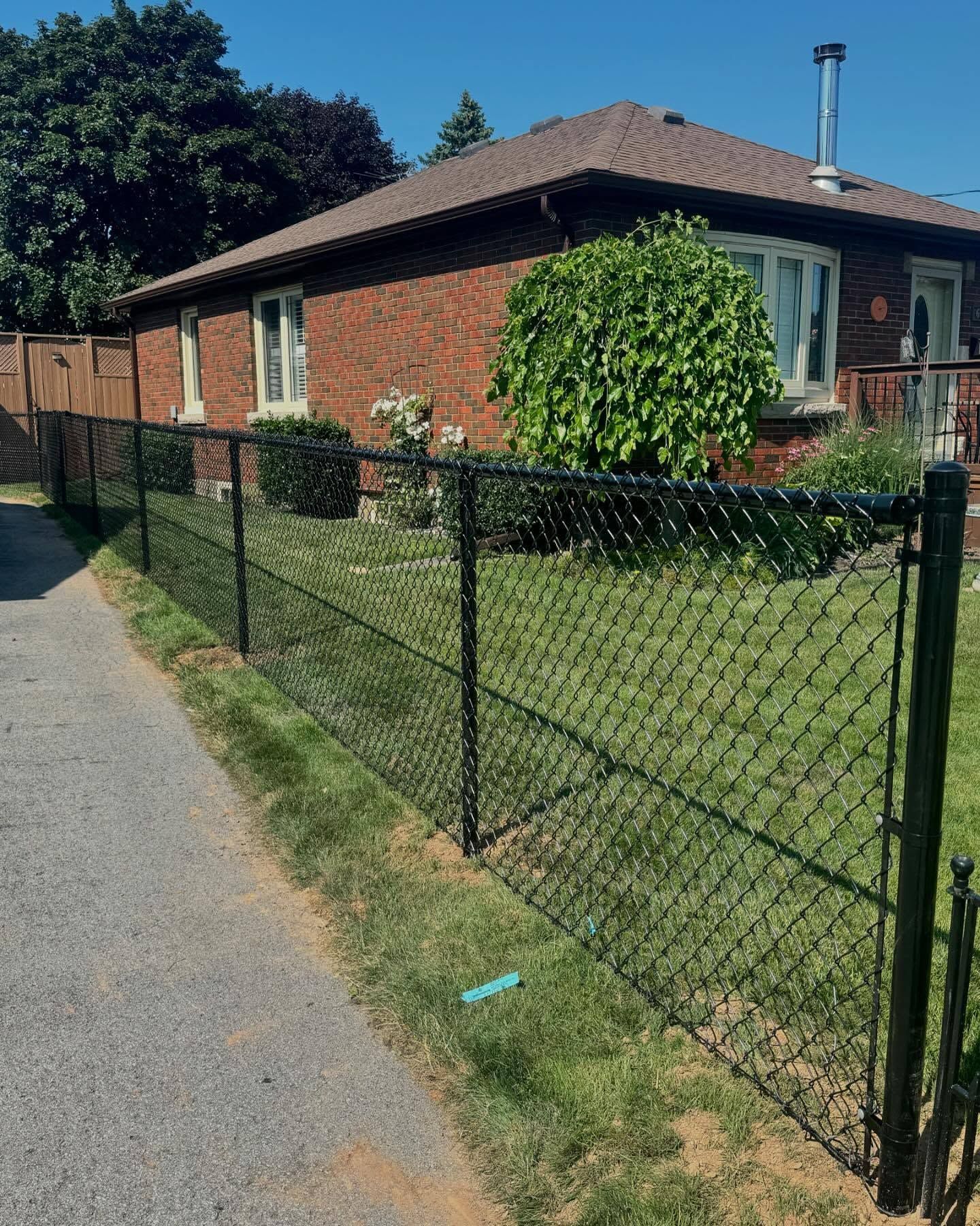 Black iron fence along a sunlit grassy path with trees and warm sunlight behind it