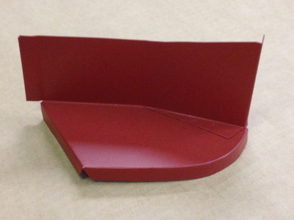 Red metal car part, with a curved lower section, angular sides, and a vertical back piece.