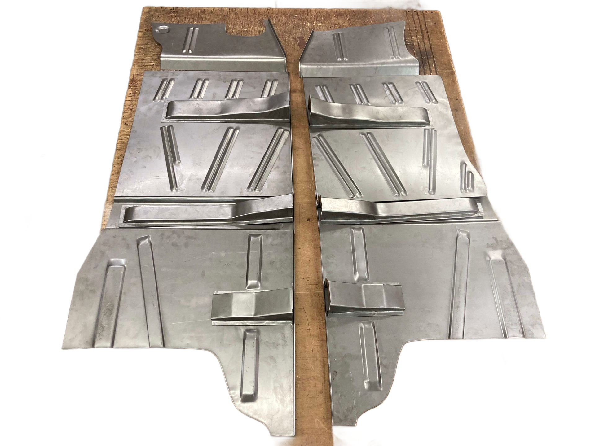 Two silver metal car floor panels on a brown surface.