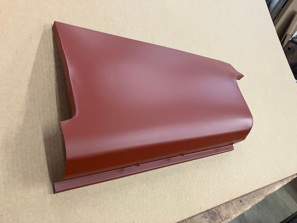 Red car body panel on a light brown surface.