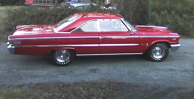 Red Ford Thunderbird coupe on a grassy field.
