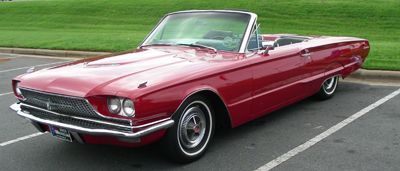 Red convertible car parked in a lot.