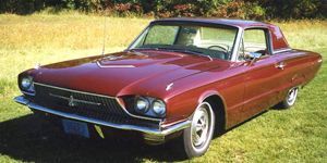 Red Ford Thunderbird coupe on a grassy field.