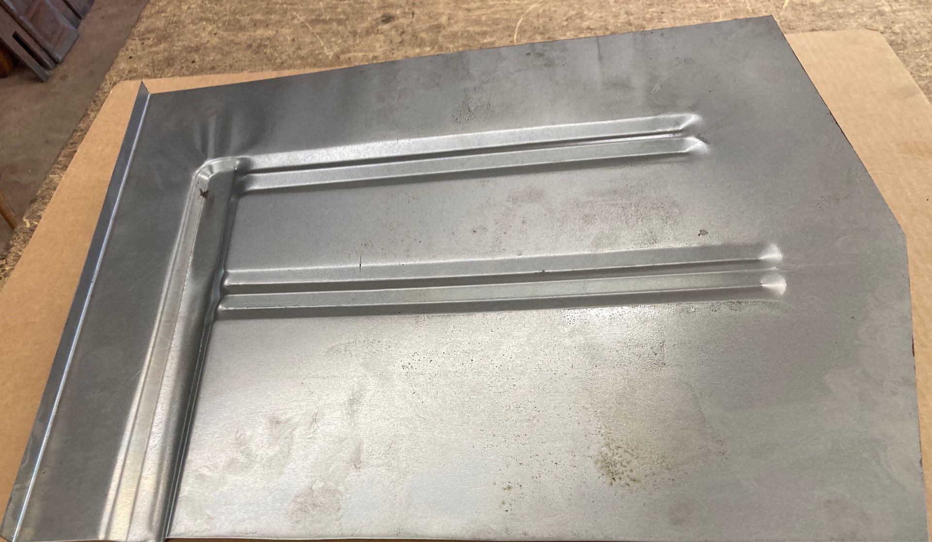 Silver metal sheet with raised ridges and bent edge.