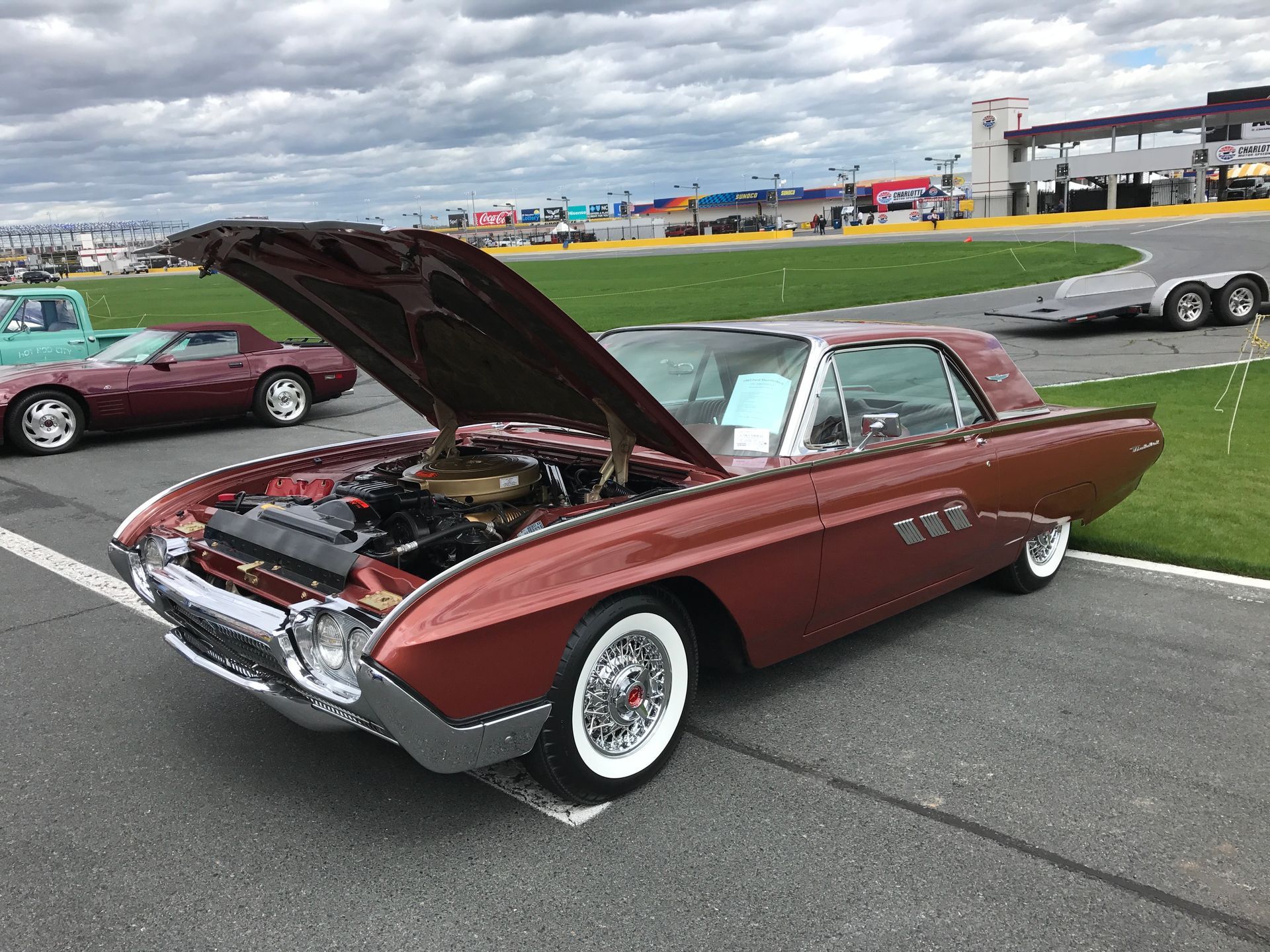 Red Ford Thunderbird coupe on a grassy field.