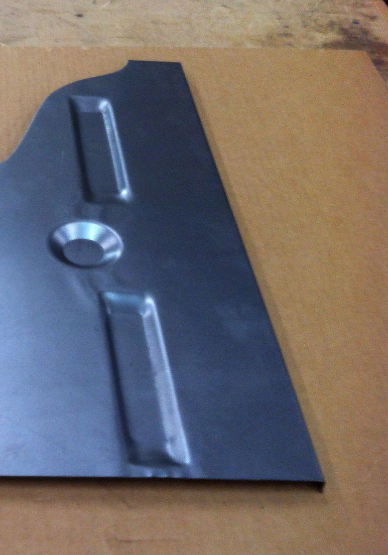 Metal car floor panel with two rectangular and one circular raised sections.
