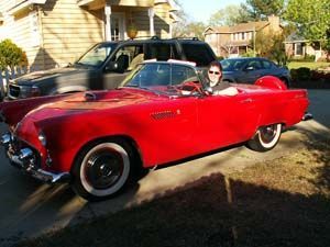Red classic convertible car with Bob Jones at the wheel, in front of a house.