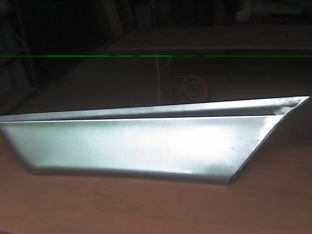 Silver, angular metal panel, possibly a car part.