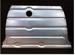 A silver metal automotive panel with horizontal ridges and a central hole.