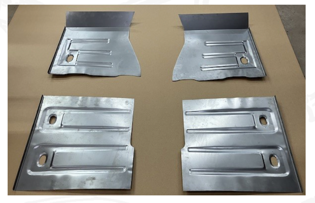 Four new metal car floor panels laid out on a surface, each with ridges and holes.