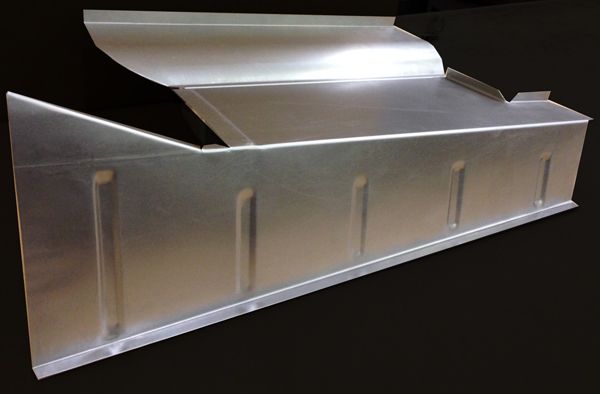 Silver metal automotive body panel on a wooden work surface.