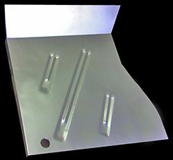 Metal car floor panel with stamped support ridges and a pre-drilled hole.