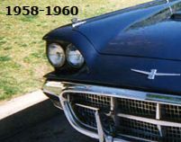 Red Ford Thunderbird coupe on a grassy field.