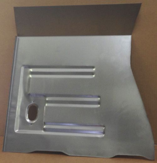 Metal car body panel with formed ridges and a hole, against a cardboard background.