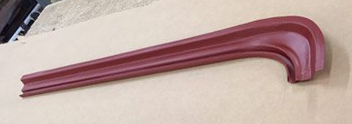 Red curved metal trim piece on a neutral surface.