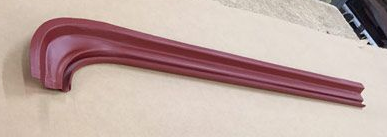 A burgundy-colored car body trim piece, curved at one end, resting on a beige surface.