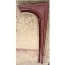 Red metal car body panel, curved with vertical support, resting on a concrete surface.