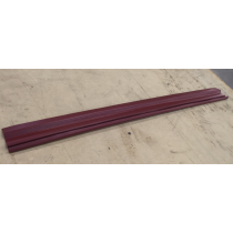 Burgundy-colored, grooved strip of material laying on a tan surface.