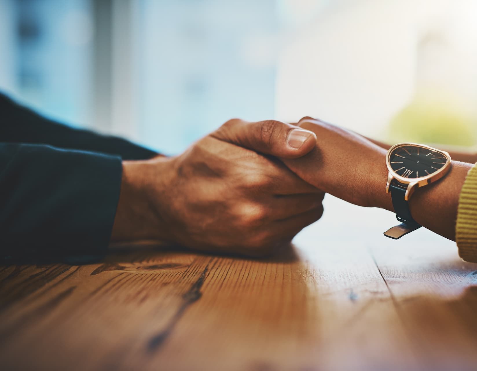 a man and a woman are holding hands on a wooden table .
