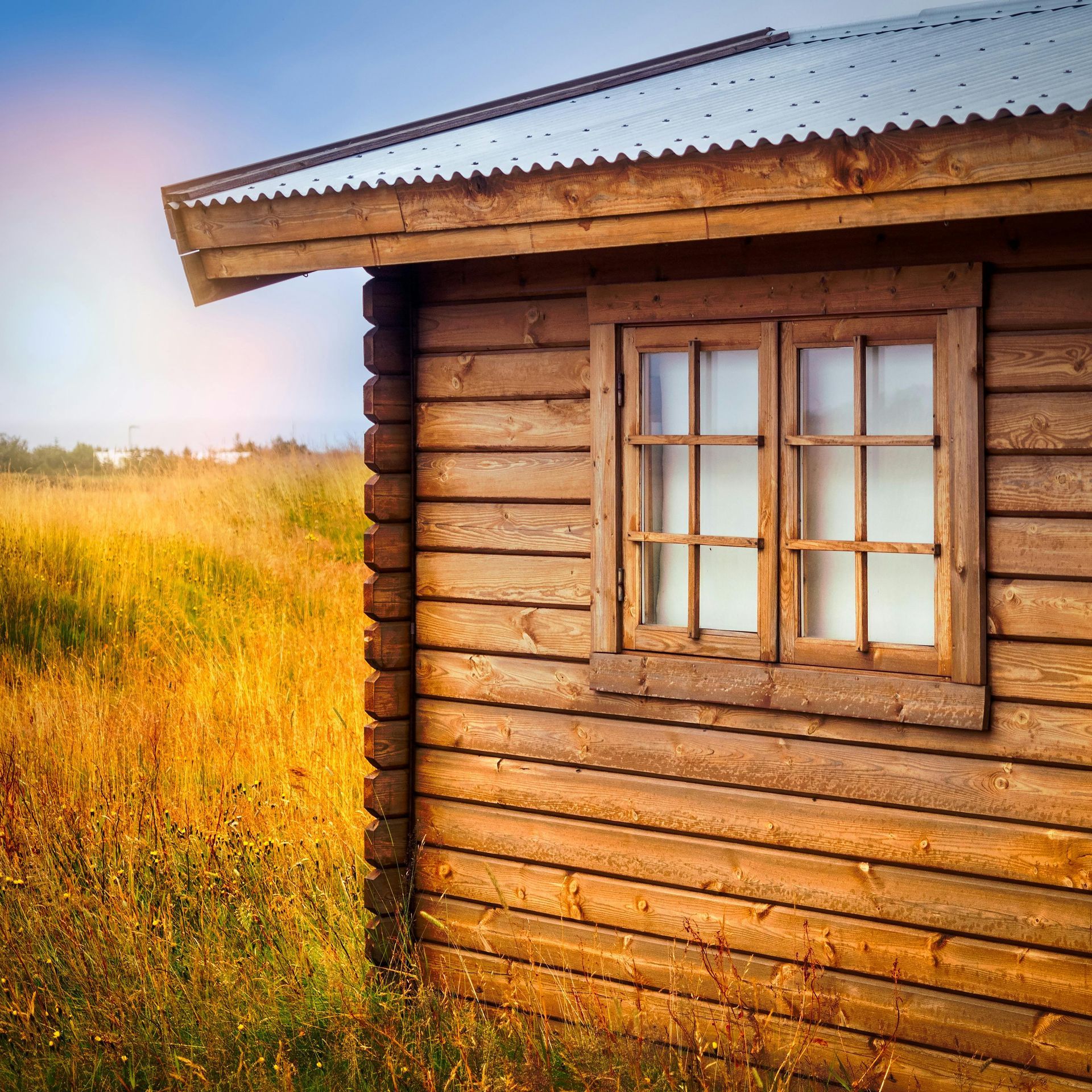 A wooden house with a window in the middle of a field