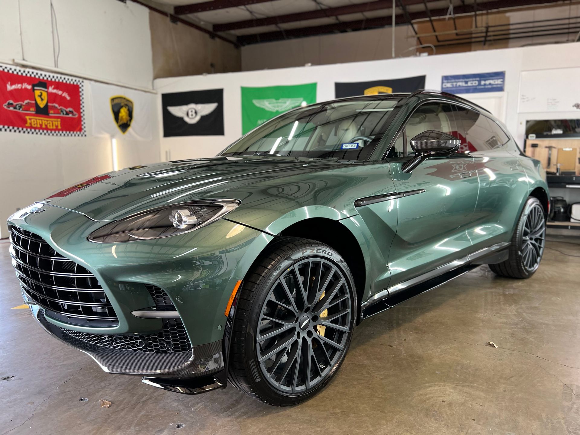 a green car is parked in front of a ferrari banner