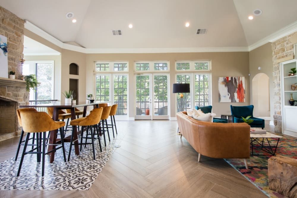 Resident clubhouse with a couch, table, chairs, and a fireplace at Marquis at Treetops in Northwest Austin, TX.