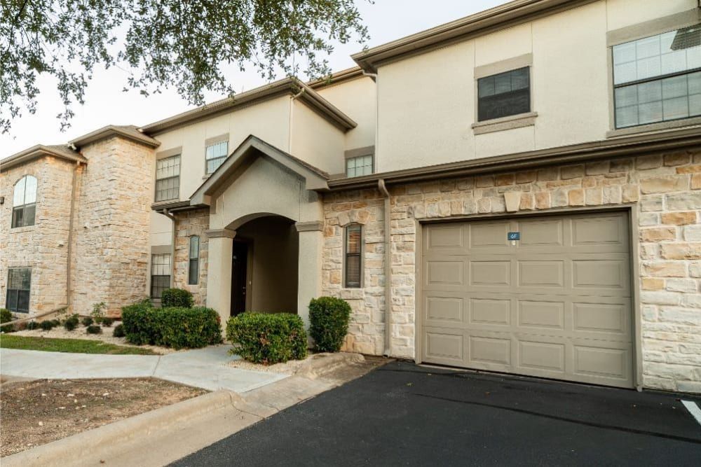 A large apartment building with a garage in front of it at Marquis at Treetops in Northwest Austin, TX.