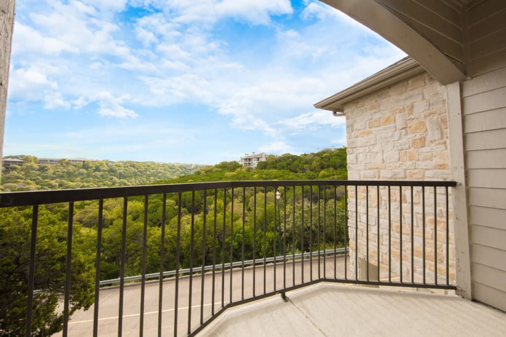 Apartment balcony with a view of a lush green forest at Marquis at Treetops in Northwest Austin, TX.