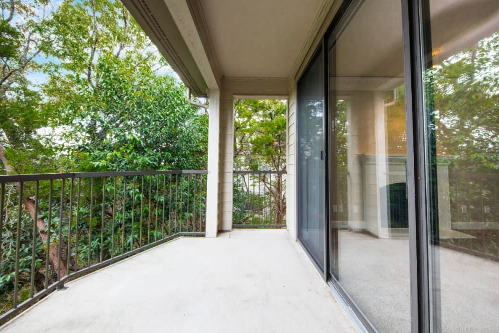 An empty balcony with sliding glass doors and trees in the background at Marquis at Treetops in Northwest Austin, TX.